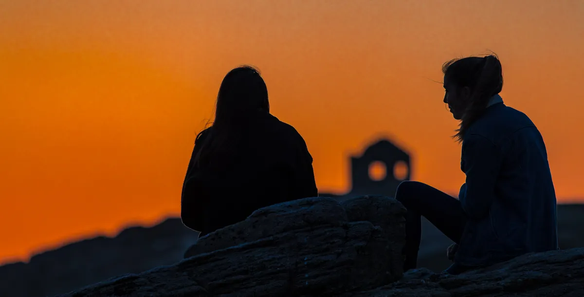Paar als Silhouette vor orangem Abendhimmel – Côte Sauvage, Bretagne