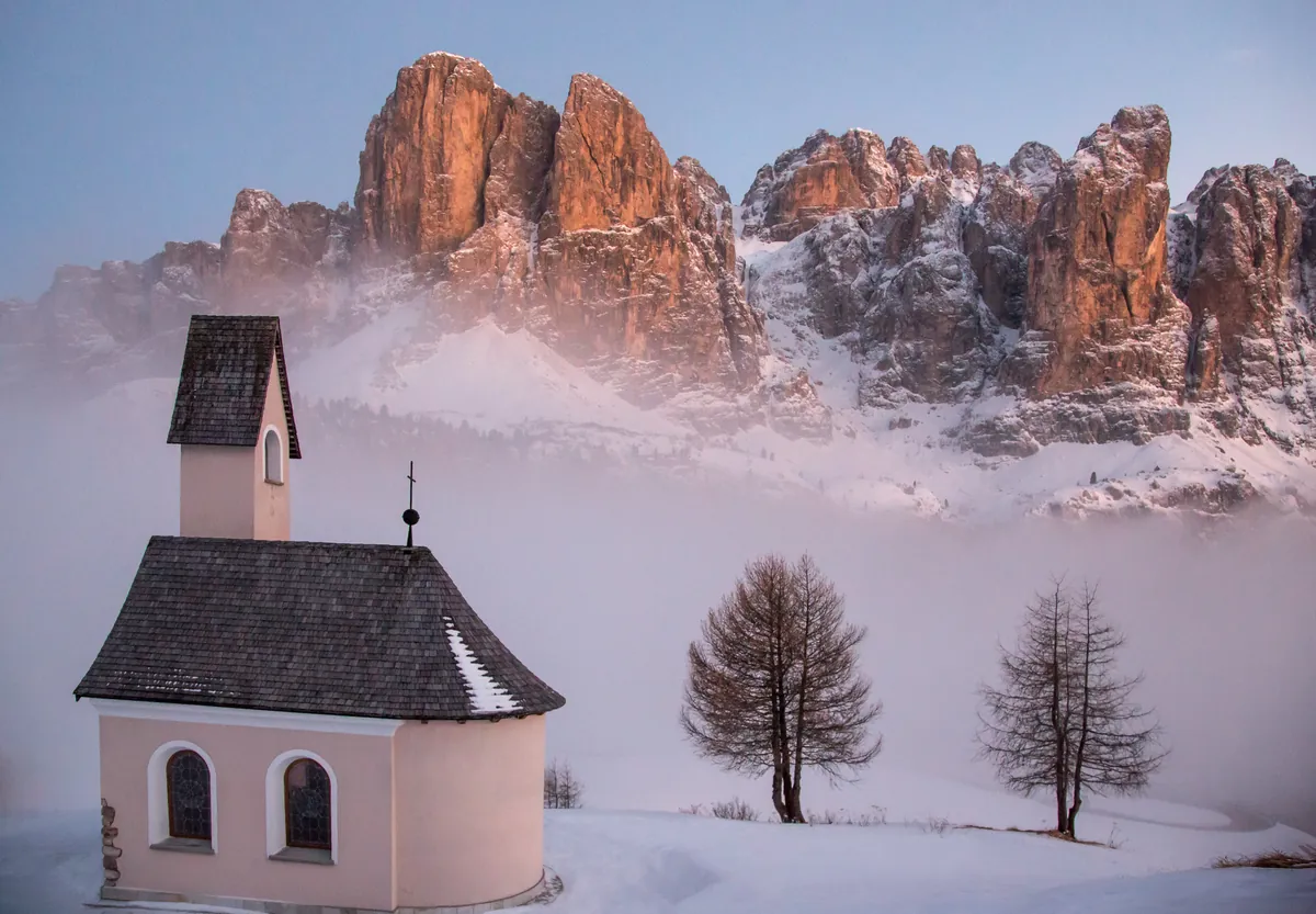 Kapelle am Grödner Joch im Nebel mit glühenden Gipfeln – Dolomiten, Südtirol