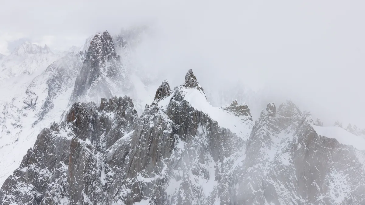 Schroffe, verschneite Felsnadeln im Mont-Blanc-Massiv im Schneetreiben – Chamonix, Frankreich